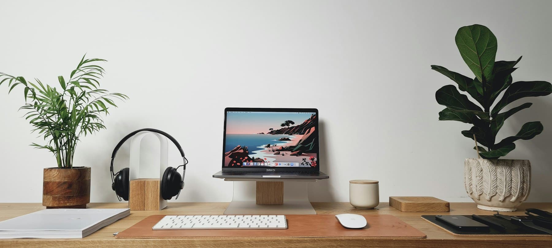 A tidy desk with a laptop between two plants
